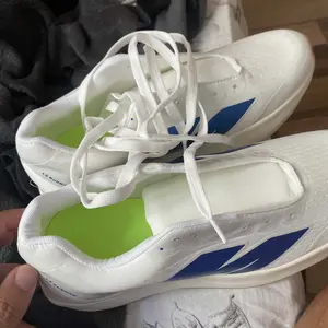Tênis branco com detalhe azul segurado pelo cliente